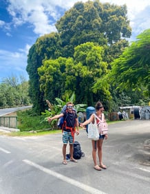 Eva and Laurent hitchhiking on a scenic road in Moorea, French Polynesia.