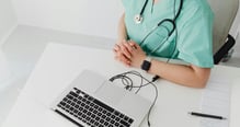 a nurse in scrub scrubs and a stethoscope on a laptop