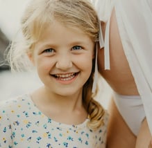 Petite fille souriante qui écoute le ventre rond de sa maman – séance photo grossesse dans le Gard