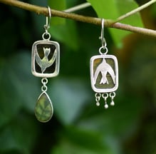 a pair of hand made earrings a bird and flower with seaglass