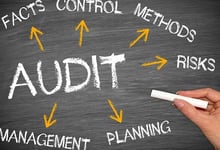 Magnifying glass over financial statements for auditing compliance.