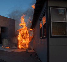 IBHS research center testing fire prevention for properties showing an engulfed structure next to another building catch fire