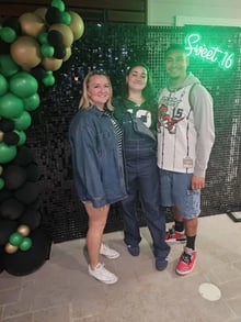 Ashlee and family in front of the black shimmer wall with sweet 16 neon sign in Logan.