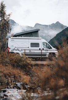 a van parked in a field with mountains in the background