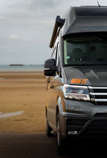 a van parked on the beach with a surfboard