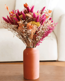 fushia and orange flowers in a terracotta vase