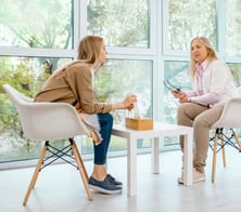 two women sitting at a table with a cup of coffee