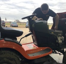 a man working on a riding lawn mower