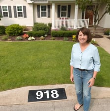 Lady standing next to her freshly painted Address number"918", very happily.