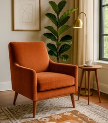 Rust-orange Mid-Century accent chair styled with lamp, art, and natural light