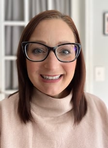 a picture of Angela Girard, a woman with glasses and a turtle neck sweater