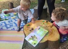 two young children playing with toys and a book
