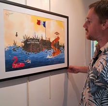 Artist closely examining a framed digital illustration of a water park scene "Splashback"