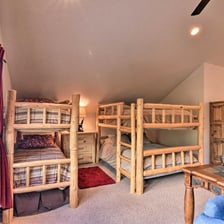 Four twin beds in rustic log bunks tucked into a lofted space.