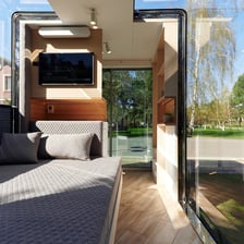 Interior of tiny home pod with bed and large glass windows