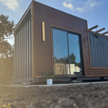 Modern tiny home pod with glass doors and wood siding