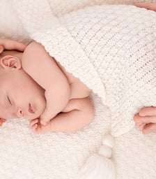 photo de bébé doucement enveloppé des mains de ses parents