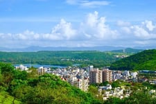 A city view with trees and mountains surrounding with blue sky