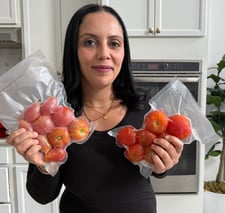 By eya holding a bag with whole frozen tomatoes 