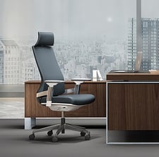 Executive high-back office chair in dark grey with headrest, at a modern wooden desk