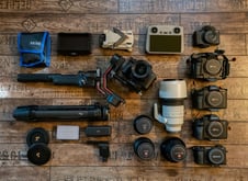 a variety of cameras and accessories on a wooden floor l wedding photographers near me 