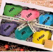 Set of cookies in a ready gift box decorated with royal icing, featuring positive words like Love, Dream, Laugh, Hope, Joy