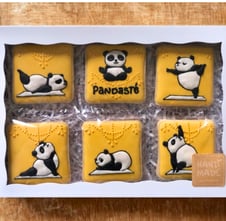Set of decorated cookies in a box featuring adorable panda-themed, crafted with royal icing, a unique treat for yoga lovers