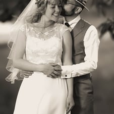 Braut und Bräutigam in eleganter Hochzeitskleidung umarmen sich im Freien.