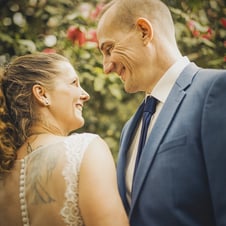  Das Bild zeigt Nahaufnahme eines lächelnden Paares, das sich bei ihrer Hochzeit ansieht. Die Frau trägt ein weißes Brautklei