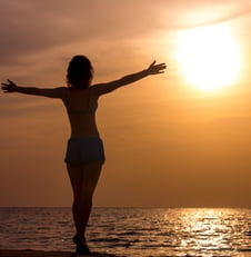 femme libre et heureuse qui regarde l'horizon en levant les bras