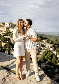 Groom kissing bride on cheek with scenic view of Gordes — South of France wedding photography cost