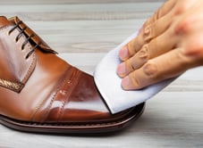 a person cleaning a shoe with a shine wipe