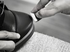 a person is removing shoe scuff with a pencil eraser