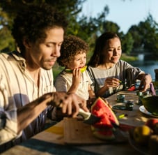 a family sitting at a table with a child eating nutritious foods