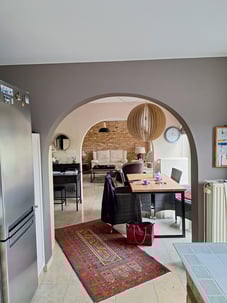 Cuisine avant transformation montrant une vue ouverte avec une arcade vers le salon