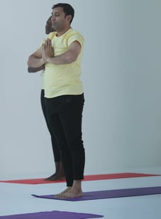 a man doing yoga with yellow shirt and black pants