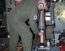 USAF personel loading a dropsonde into chamber that will shortly release it from moving aircraft.