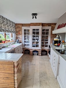 Cuisine avant transformation avec des meubles bas, du plan de travail et des éléments en briques