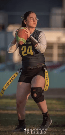 a woman in a black and white uniform holding a football ball