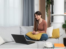 a woman sitting on a couch with a laptop and headphones