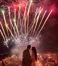 Vibrant fireworks display synchronized with music at a Santorini wedding party.