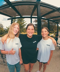 three girls hugging ad smiling