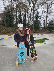 two girls holding a skateboard