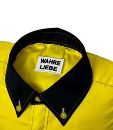a yellow shirted pillow with a black collar and label