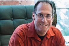 a man in a red shirt and jeans sitting in a chair