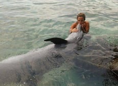 a woman in a bikini top is holding a dolphin