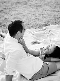 Black and white couple photo in Provence field — she rests on his legs and caresses his cheek