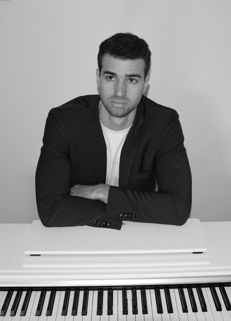a man in a suit and tie sitting at a piano