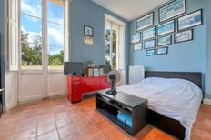 Chambre lumineuse avec vue sur le terrain boisé, dans une maison de maître, par un photographe immobilier à Toulon.