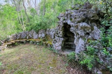 Photographie d'une grotte naturelle sur un terrain boisé d'une maison de maître, capture par photographe immobilier.